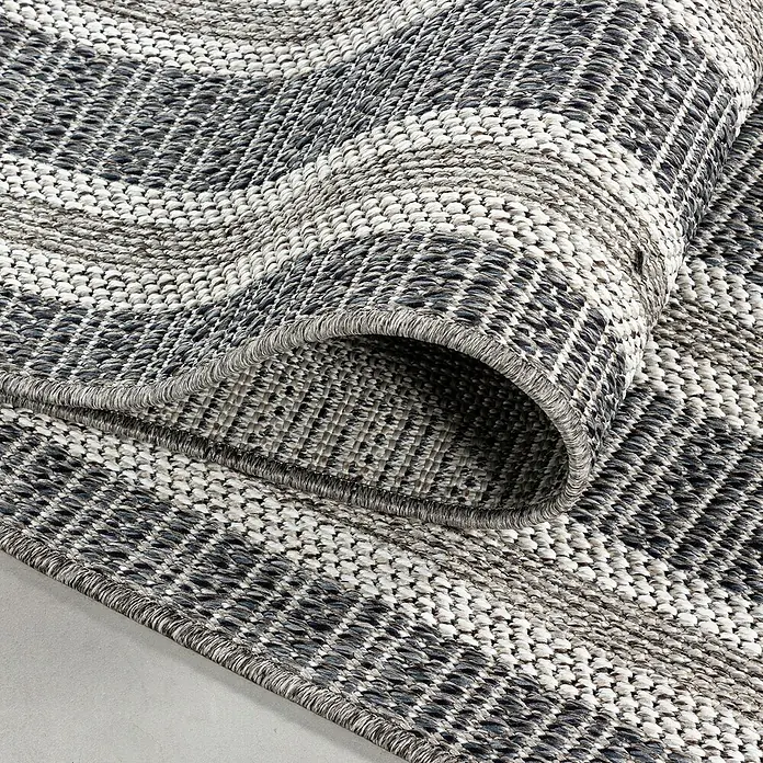 Outdoor-Teppich Aruba 4901Grau, 230 x 160 cm, 100% Polypropylen - Nahaufnahme eines gerollten grauen Teppichs mit gewebtem Muster, der Textur und Design hervorhebt.