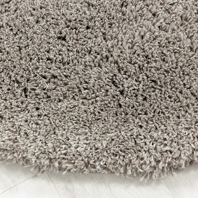 Hochflorteppich Fluffy 3500 - Beige, 370 x 280 cm, 100 % Polypropylen - Nahaufnahme eines weichen, grauen Shaggy-Teppichs auf einem hellen Holzboden, der eine gemütliche Textur und Wärme ausstrahlt.
