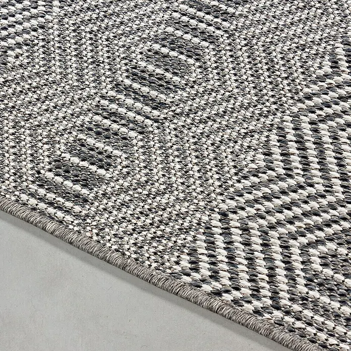 Outdoor-Teppich Aruba 4903 - Grau, 150 x 80 cm, 100% Polypropylen - Detailansicht eines grau-weißen Teppichs mit geometrischem Muster. Der Teppich liegt auf einem grauen Untergrund und zeigt eine feine Webstruktur mit dunklen Akzenten.