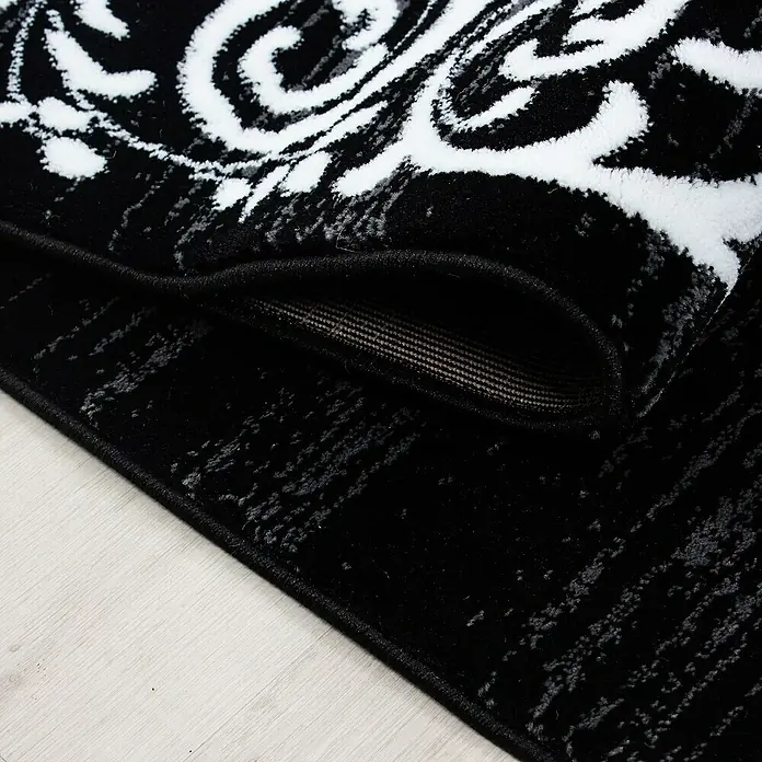 Kurzflorteppich Miami 6620Schwarz, 300 x 80 cm, 100 % Polypropylen - Detailaufnahme eines schwarzen Teppichs mit elegantem, weißem Muster, der eine luxuriöse und stilvolle Atmosphäre verspricht.