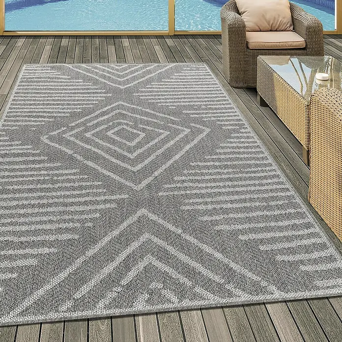 Outdoor-Teppich Aruba 4902Grau, 200 x 140 cm, 100% Polypropylen - Detailaufnahme eines grau-weißen Outdoor-Teppichs mit geometrischem Muster auf einer Holzterrasse, der eine stilvolle Atmosphäre schafft.