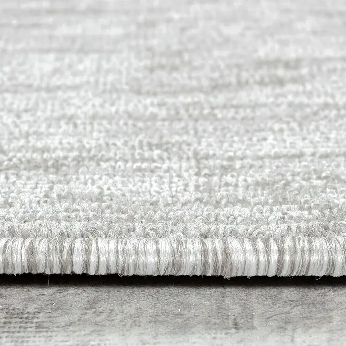 Flachgewebeteppich Nizza 1800Cream, 290 x 200 cm, 100 % Polypropylen - Nahaufnahme eines weißen Teppichs, der die Textur und die Kantenverarbeitung des Produkts hervorhebt.