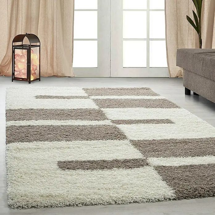 Hochflorteppich Gala 2505 - Beige, 370 x 280 cm, 100% Polypropylen - Ein rechteckiger Teppich mit einem geometrischen Muster aus weißen und braunen Rechtecken liegt auf einem hellen Holzboden.