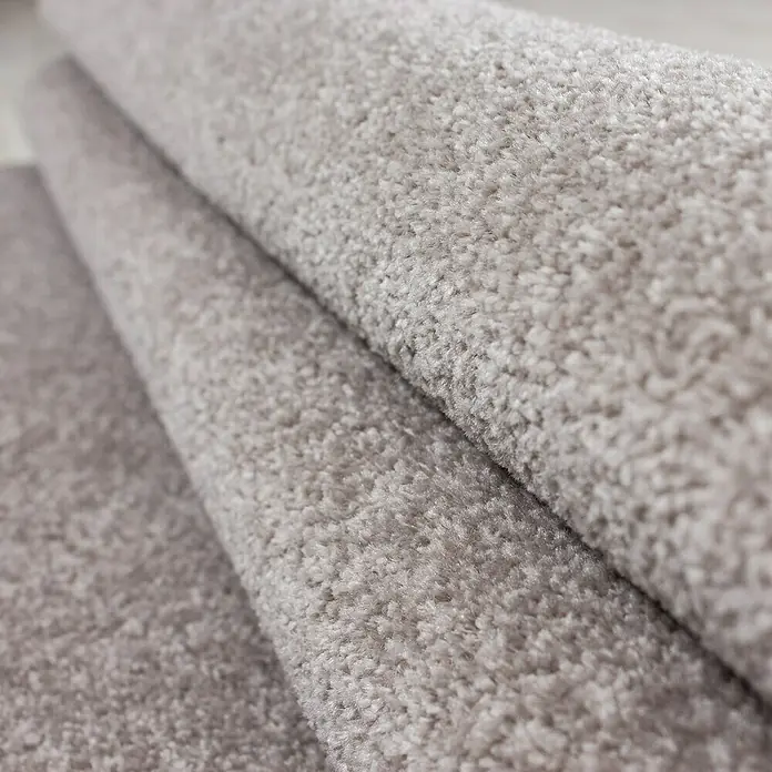 Kurzflorteppich Ata 7000 - Beige, 170 x 120 cm, 100 % Polypropylen - Nahaufnahme eines grauen, gerollten Teppichs mit weicher Textur. Ideal für Wohnräume, die Komfort und Wärme ausstrahlen.
