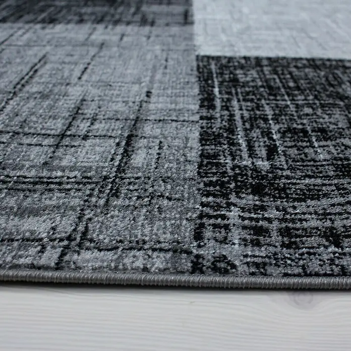 Kurzflorteppich Plus 8001Schwarz, 230 x 160 cm, 100% Polypropylen - Nahaufnahme eines modernen Teppichs mit abstraktem Muster in Grau- und Schwarztönen, ideal für ein stilvolles Zuhause.