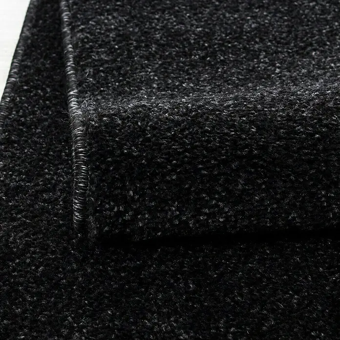 Kurzflorteppich Ata 7000 - Anthrazit, 250 x 80 cm, 100 % Polypropylen - Nahaufnahme eines schwarzen, hochflorigen Teppichs, der seine Textur und Verarbeitung hervorhebt.\n