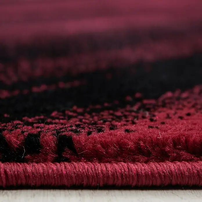 Kurzflorteppich Miami 6630Rot, 150 x 80 cm, 100% Polypropylen - Nahaufnahme eines modernen Teppichs mit einem abstrakten Design in Schwarz und Burgunderrot. Die Textur des Teppichs ist deutlich sichtbar.