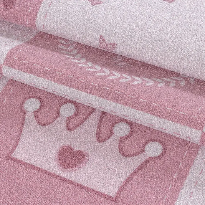 Kinderteppich Play 2905 - Pink, 200 x 140 cm, 100% Polyamide - Nahaufnahme eines rosa Kinderteppichs mit Kronenmuster und zarten Verzierungen, ideal für ein liebevolles Kinderzimmer.