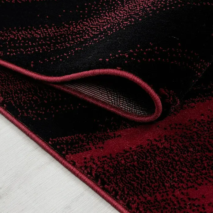 Kurzflorteppich Miami - Rot, 340 x 240 cm, 100 % Polypropylen - Detailaufnahme eines modernen Teppichs in Schwarz und Burgunderrot mit abstraktem Muster und umgeschlagener Kante.
