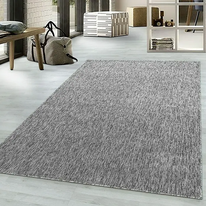 Flachgewebeteppich Nizza 1800 - Light Grey, 150 x 80 cm, 100% Polypropylen - Ein grauer Teppich mit subtiler Textur liegt auf einem hellen Holzboden in einem modernen Raum.