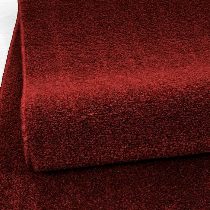 Kurzflorteppich Ata 7000Rot, 230 x 160 cm, 100% Polypropylen - Nahaufnahme eines burgunderroten Teppichs, der die Textur und Farbe des weichen, gewebten Materials hervorhebt.