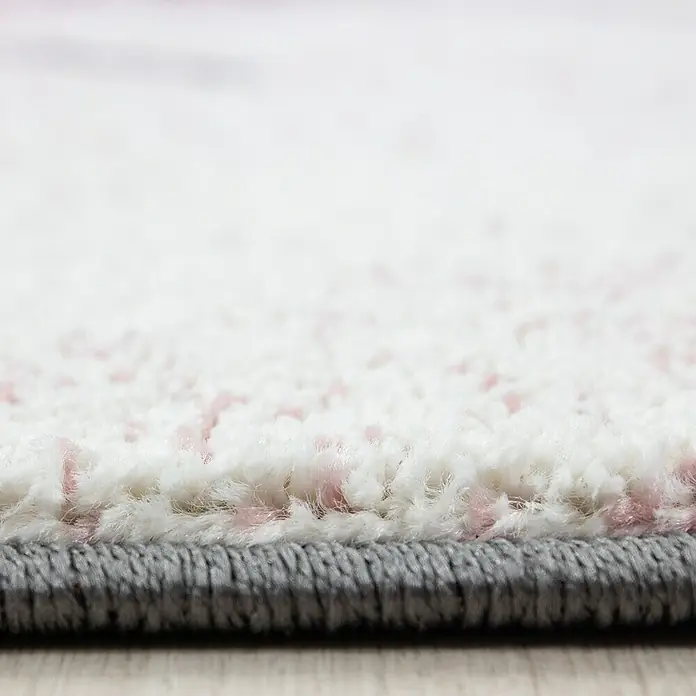 Kinderteppich Kids 0560 - Pink, 200 x 140 cm, 100 % Polypropylen - Detailaufnahme eines flauschigen Teppichs mit weißen und rosafarbenen Fasern und grauem Rand, der eine weiche und stilvolle Textur zeigt.