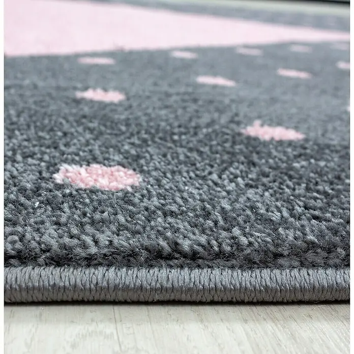 Kinderteppich Bambi 0830Pink, 150 x 80 cm, 100 % Polypropylen - Detailaufnahme eines grauen Teppichs mit rosa Punktmuster und einer sauber verarbeiteten Kante. Ein stilvolles Element für jeden Raum.
