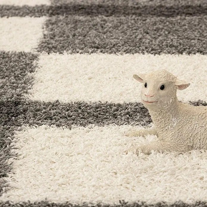Hochflorteppich Gala 2505 - Light Grey, 250 x 80 cm, 100% Polypropylen - Eine Nahaufnahme eines weissen Lämmchens auf einem modernen Teppich mit geometrischem Muster, ideal für Kinderzimmer oder als Dekoration.