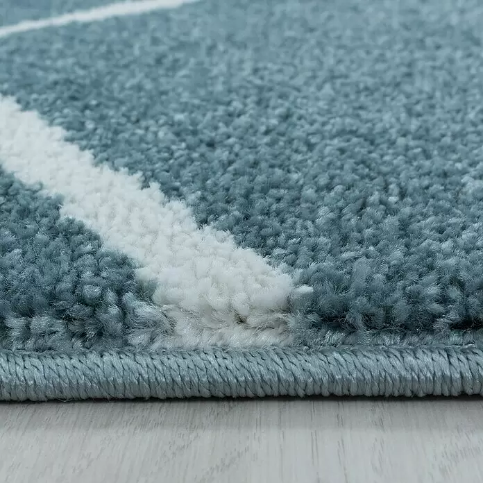 Hochflorteppich Rio 4602 - Blau, 250 x 80 cm, 100% Polypropylen - Nahaufnahme eines weichen, blau-weißen Teppichs mit geometrischem Muster, der seinen flauschigen Flor und die Kante zeigt.