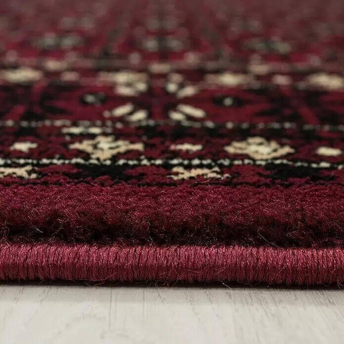 Kurzflorteppich Orient-Optik Marrakesh 0351 - Rot, 170 x 120 cm, 100% Polypropylen - Nahaufnahme eines tiefroten, gemusterten Teppichs, der seinen weichen Flor und die saubere Kante zeigt.