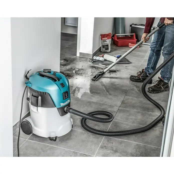 Makita Elektro-Nass- & Trockensauger VC2512L - 1.000 W, 25 l - Bild eines Nass- und Trockensaugers von Makita, der an eine Person angeschlossen ist, die Schmutz aufsaugt.