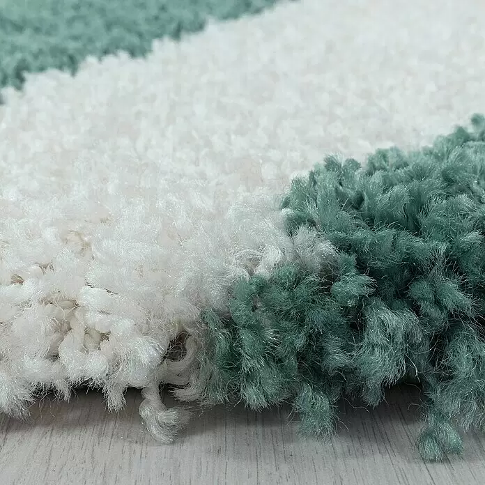 Hochflorteppich Tango 3101 - Blau, 250 x 80 cm, 100% Polypropylen - Nahaufnahme eines plüschigen, zotteligen Teppichs mit weissen und türkisfarbenen Fasern in einem Streifenmuster.