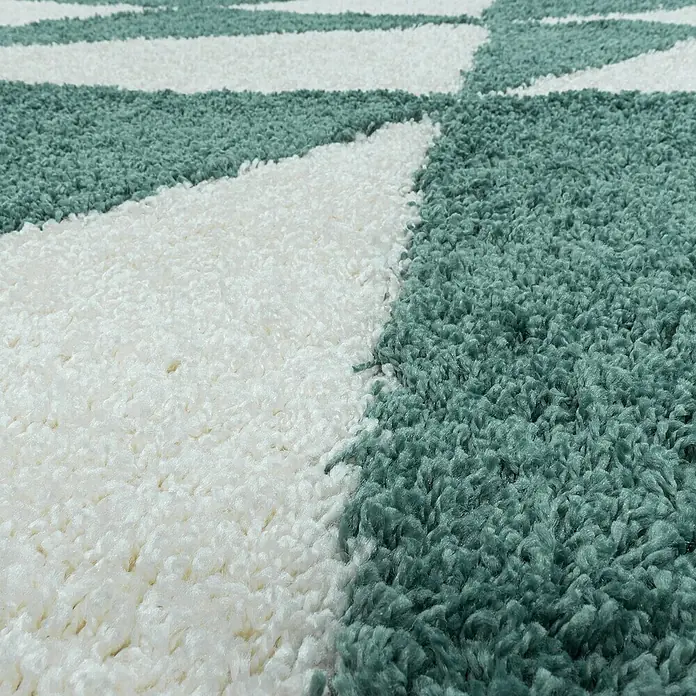 Hochflorteppich Tango 3101 - Blau, 250 x 80 cm, 100% Polypropylen - Detailaufnahme eines Teppichs mit weiß-grünem Muster. Die weichen Fasern und das moderne Design des Teppichs sind gut erkennbar.