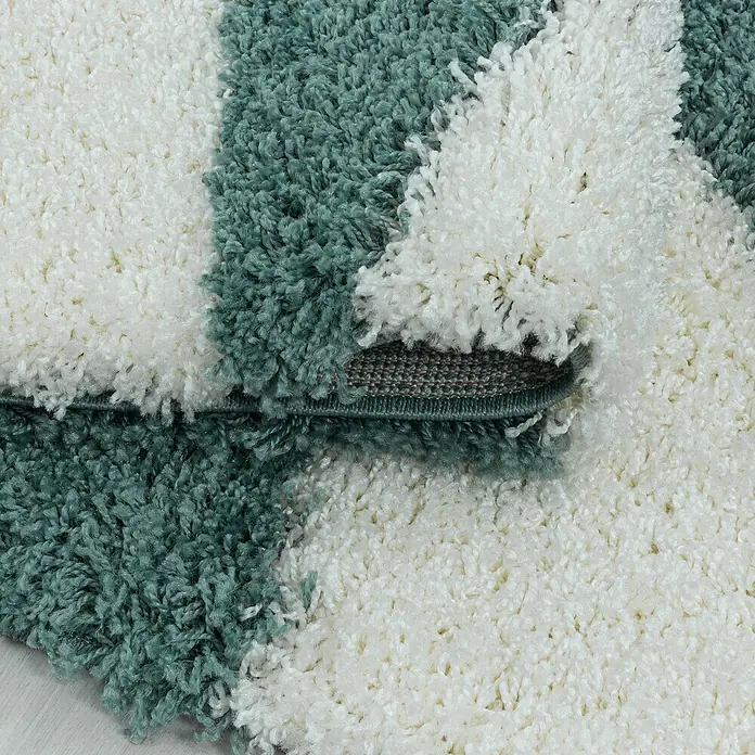 Hochflorteppich Tango 3101 - Blau, 250 x 80 cm, 100% Polypropylen - Detailaufnahme eines Shaggy-Teppichs mit weißen und grünen Streifen, der eine weiche und flauschige Textur zeigt.