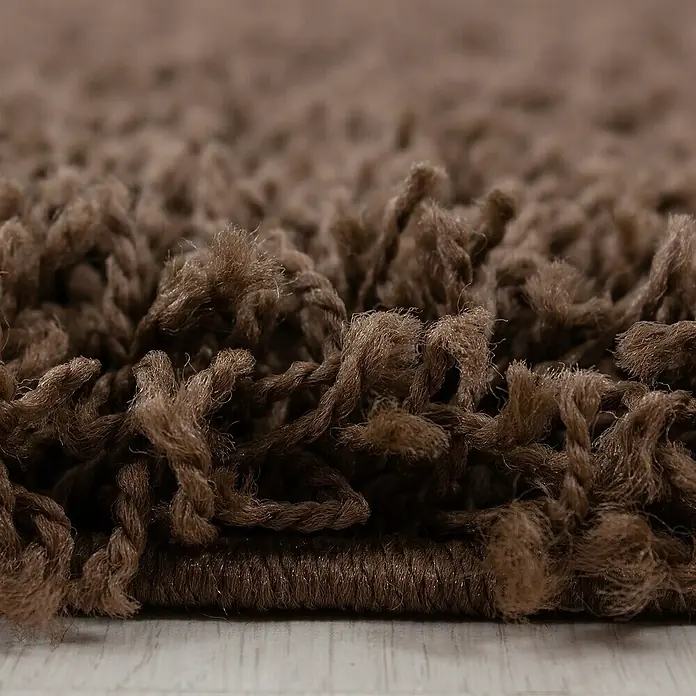 Hochflorteppich Dream 4000Braun, Durchmesser: 120 cm, 100 % Polypropylen - Nahaufnahme eines zotteligen Teppichs in dunklem Braun, der Textur und Komfort hervorhebt.