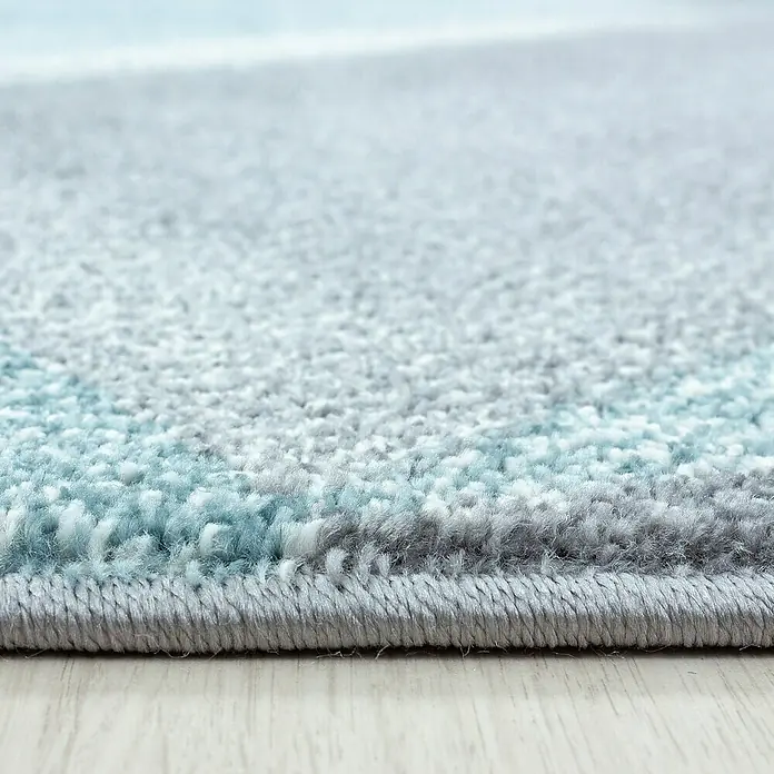 Kurzflorteppich Beta 1130Blau, 230 x 160 cm, 100 % Polypropylen - Nahaufnahme eines grauen Teppichs mit blauen Akzenten und einer sauberen Kante auf hellem Holzboden.