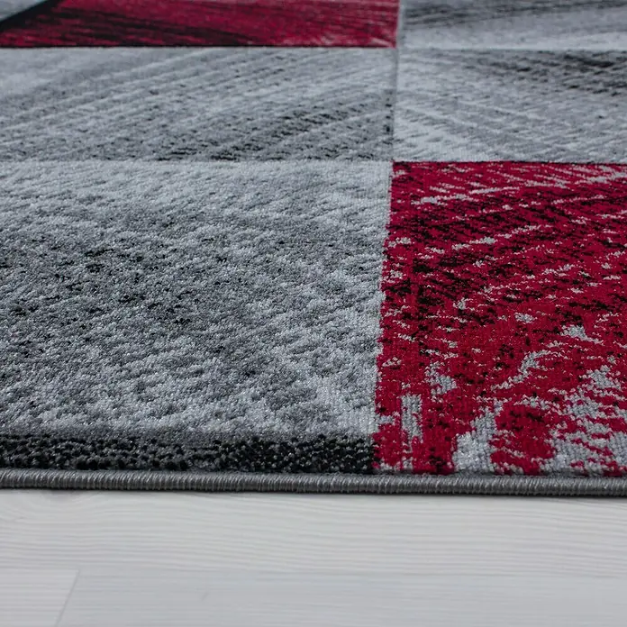 Kurzflorteppich Plus 8003Rot, 230 x 160 cm, 100% Polypropylen - Nahaufnahme eines modernen Teppichs mit geometrischen Formen in Grau- und Rottönen, der Textur und Stil vereint.