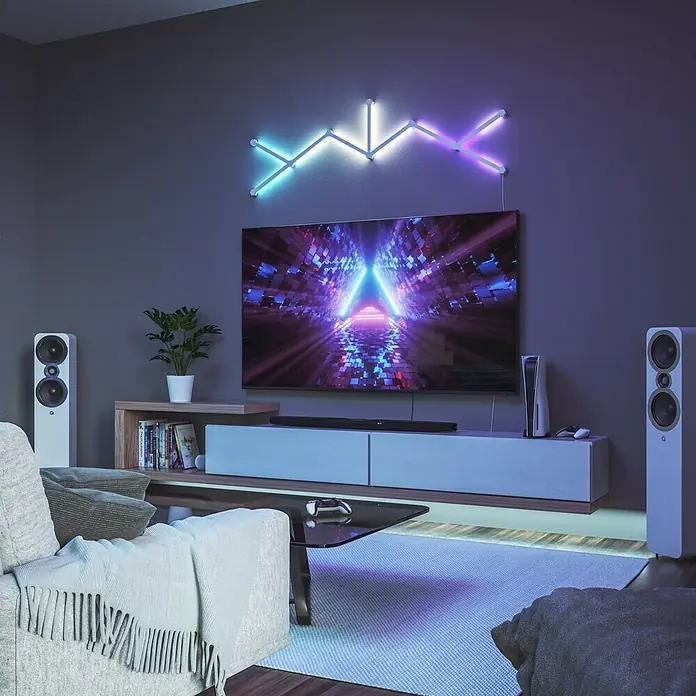 Nanoleaf Erweiterungskit Lines 60 Degrees 3 Lines - 3 Stk., Weiß, RGBW - Wohnzimmer mit TV-Gerät, Lautsprechern und dekorativer Nanoleaf Lines Beleuchtung an der Wand, die ein modernes Ambiente schafft.