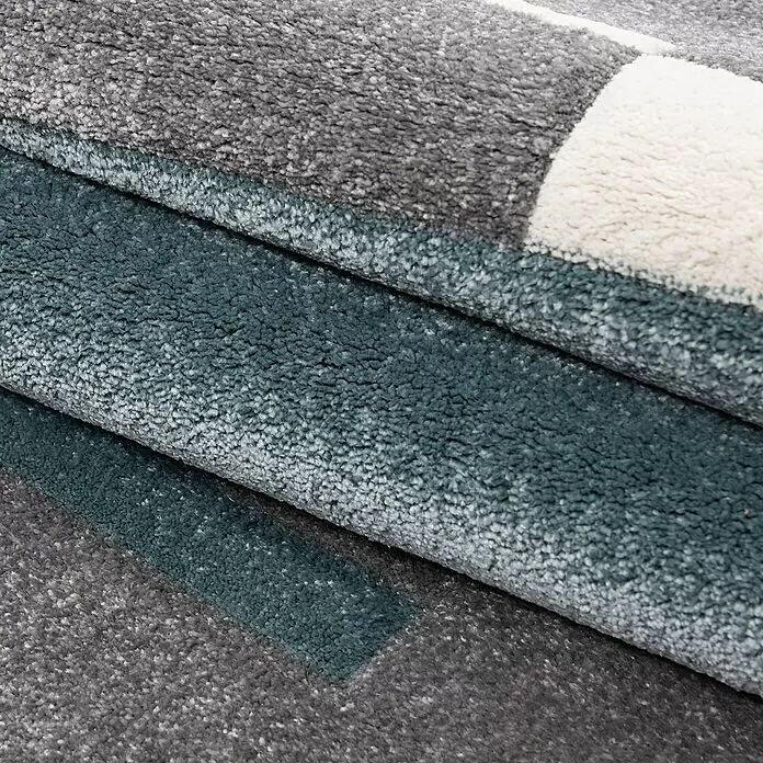Kurzflorteppich Hawaii 1310 - Blau, 340 x 240 cm, 100 % Polypropylen - Nahaufnahme eines gefalteten Hochflorteppichs in Grau, Petrol und Wollweiß, der seine weiche Textur zeigt.