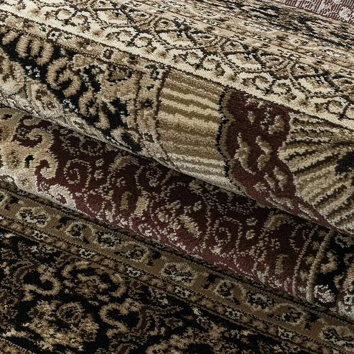 Kurzflorteppich Kashmir 2605Rot, 150 x 80 cm, 100 % Polypropylen - Detailaufnahme eines zusammengerollten Teppichs mit braunen und beigen Mustern.