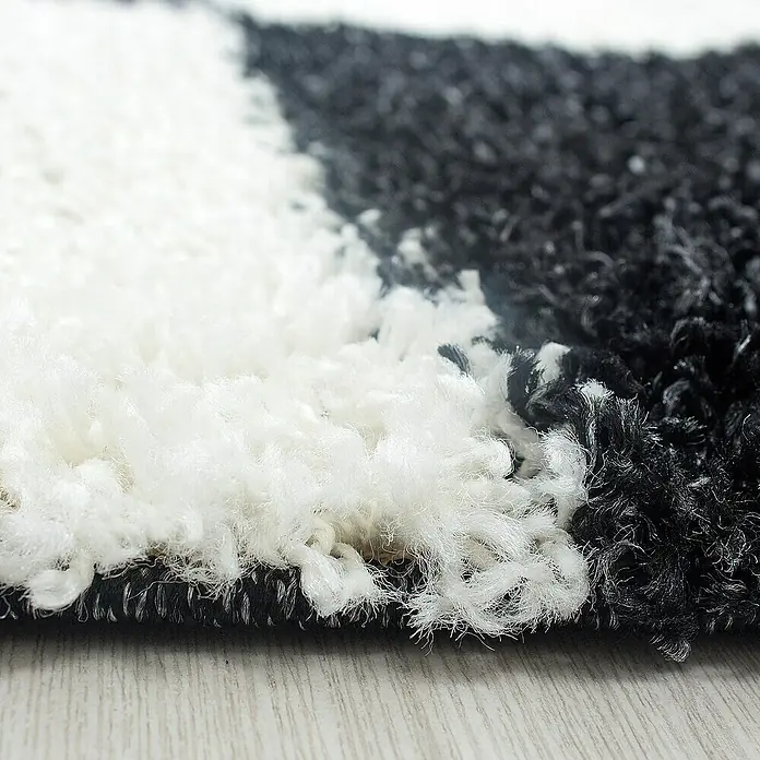 Hochflorteppich Life 1501Schwarz, 170 x 120 cm, 100% Polypropylen - Nahaufnahme eines flauschigen Teppichs mit einem abstrakten Schwarz-Weiß-Muster, der eine weiche Textur und ein modernes Design zeigt.