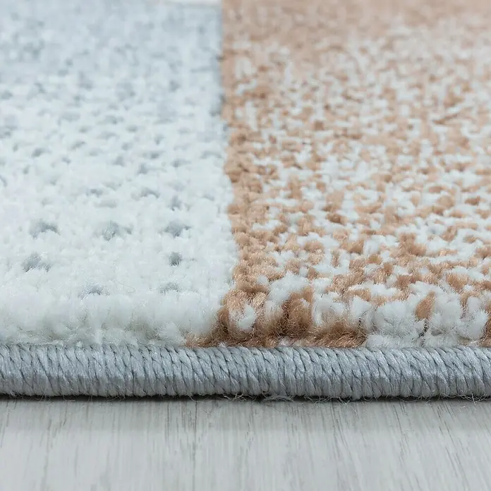 Hochflorteppich Rio 4603 - Kupfer, 170 x 120 cm, 100% Polypropylen - Nahaufnahme eines modernen Teppichs mit geometrischem Muster in Weiß, Grau und Beige, der eine stilvolle und komfortable Ergänzung für jeden Raum darstellt.