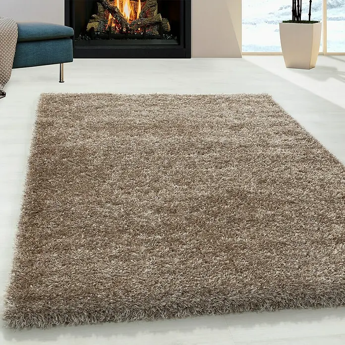 Hochflorteppich Brilliant 4200Taupe, 110 x 60 cm, 100% Polyester - Ein weicher, beiger Teppich liegt auf einem hellen Holzboden und sorgt für Wärme und Komfort im Raum.