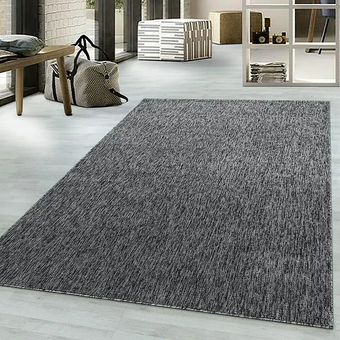 Flachgewebeteppich Nizza 1800 - Grau, 230 x 160 cm, 100% Polypropylen - Ein grauer Teppich liegt in einem hellen Raum und verleiht dem Interieur einen modernen Touch. Das Muster des Teppichs ist dezent und elegant.