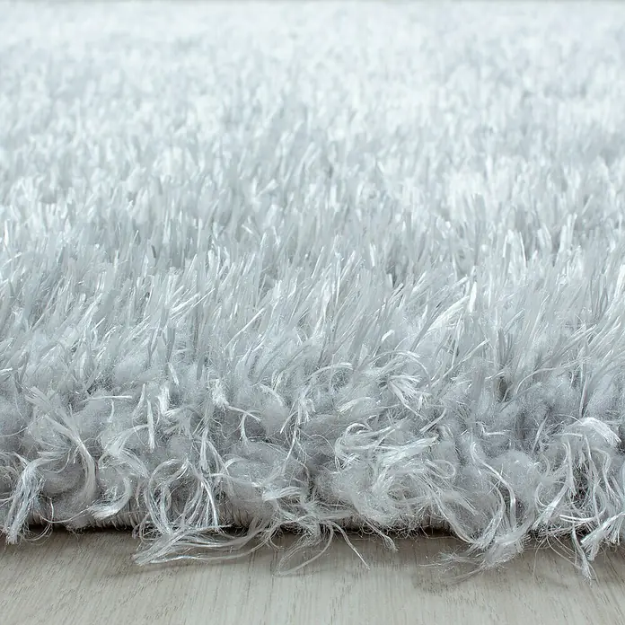 Hochflorteppich Brilliant 4200Silber, Durchmesser: 200 cm, 100% Polyester - Nahaufnahme eines weichen, hellgrauen Shaggy-Teppichs mit langen, zotteligen Fasern, ideal für Wohnräume, um Wärme und Komfort zu spenden.