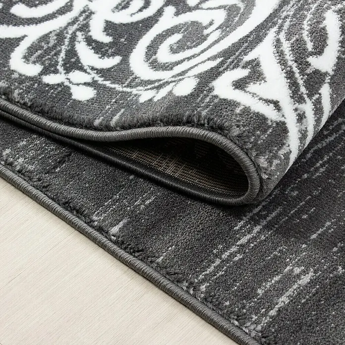 Kurzflorteppich Miami 6620 - Grau, 150 x 80 cm, 100% Polypropylen - Nahaufnahme eines eleganten grauen Teppichs mit einem weißen, floralen Muster und einer dekorativen Bordüre.