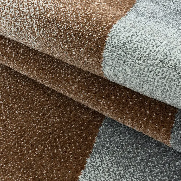 Hochflorteppich Rio 4603Kupfer, 200 x 140 cm, 100% Polypropylen - Nahaufnahme eines Teppichs mit braunen und grauen Farbblöcken, der eine weiche Textur und ein modernes Design aufweist.
