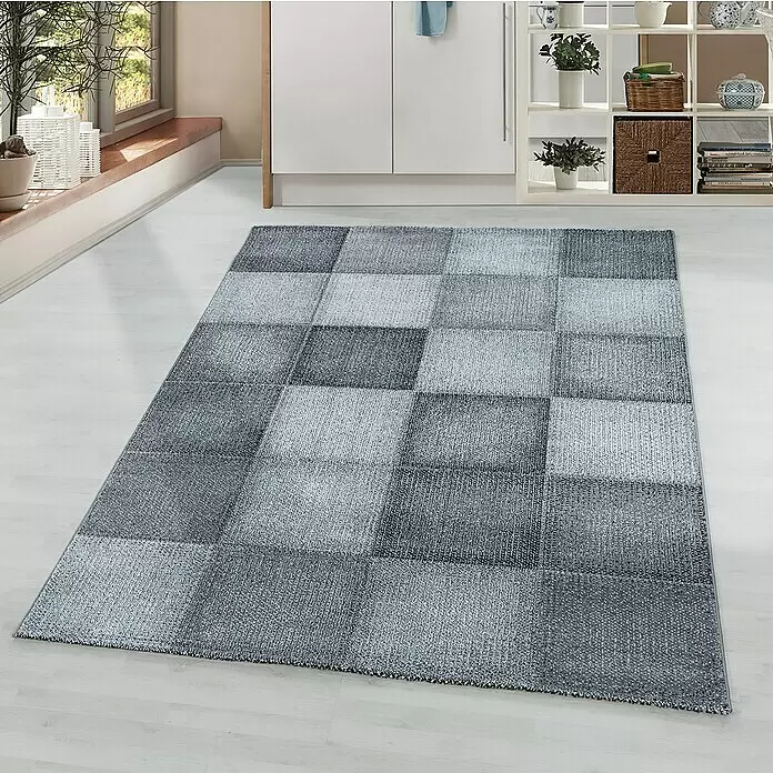 Kurzflorteppich Ottawa 4202 - Grau, 170 x 120 cm, 100 % Polypropylen - Ein karierter grauer Teppich in verschiedenen Grauabstufungen liegt auf hellem Boden in einem modernen Raum.