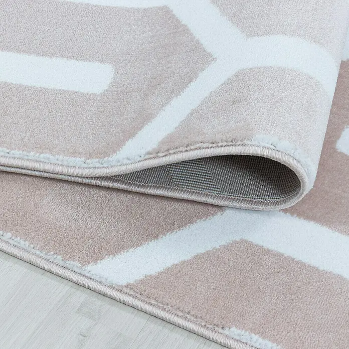 Kurzflorteppich Costa 3524 - Pink, 290 x 200 cm, 100 % Polypropylen - Nahaufnahme eines beigefarbenen Teppichs mit weißem geometrischen Muster, der eine weiche Textur und eine umgeschlagene Kante zeigt.