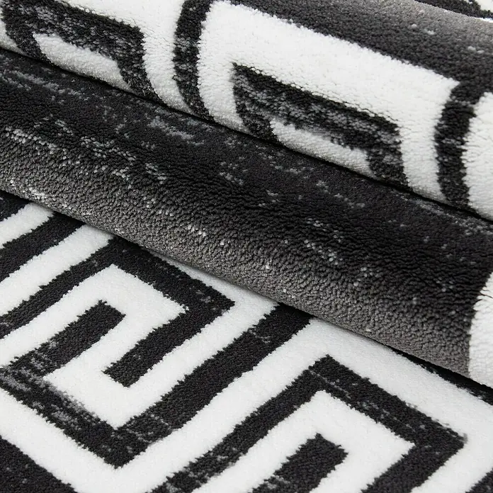 Kurzflorteppich Miami 6620Grau, 170 x 120 cm, 100% Polypropylen - Nahaufnahme eines Teppichs mit einem schwarz-weißen geometrischen Mäandermuster, der Textur und Design hervorhebt.