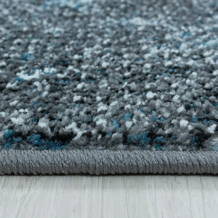 Kurzflorteppich Ottawa 4203 - Blau, 150 x 80 cm, 100% Polypropylen - Nahaufnahme eines grauen Teppichs mit blauen und weißen Akzenten, der eine weiche, strukturierte Oberfläche zeigt.