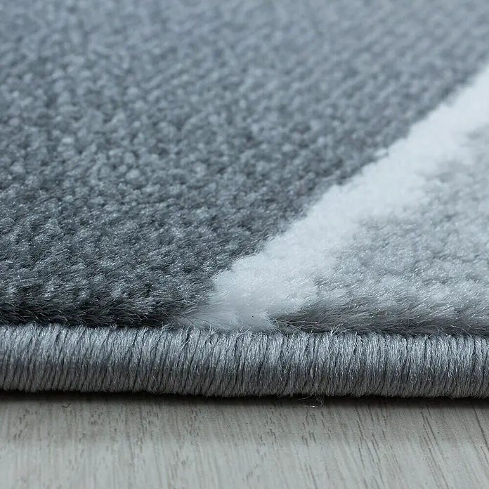Kurzflorteppich Costa 3523Grau, 290 x 200 cm, 100 % Polypropylen - Nahaufnahme eines Teppichs mit abstraktem Muster in Grau- und Weißtönen, der eine weiche Textur und einen dicken Rand aufweist.