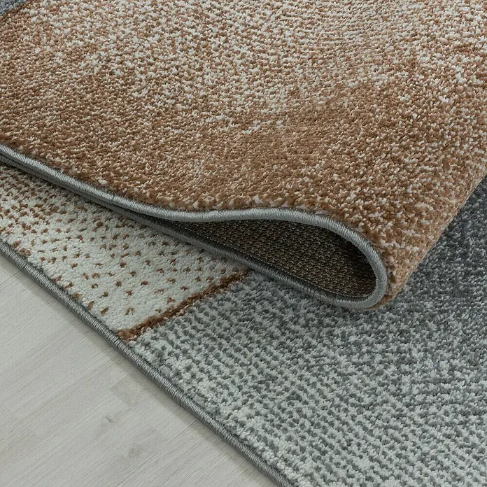 Hochflorteppich Rio 4603 - Kupfer, 170 x 120 cm, 100% Polypropylen - Detailaufnahme eines modernen Teppichs mit geometrischen Mustern in Braun-, Grau- und Weißtönen. Die Textur ist weich und einladend.