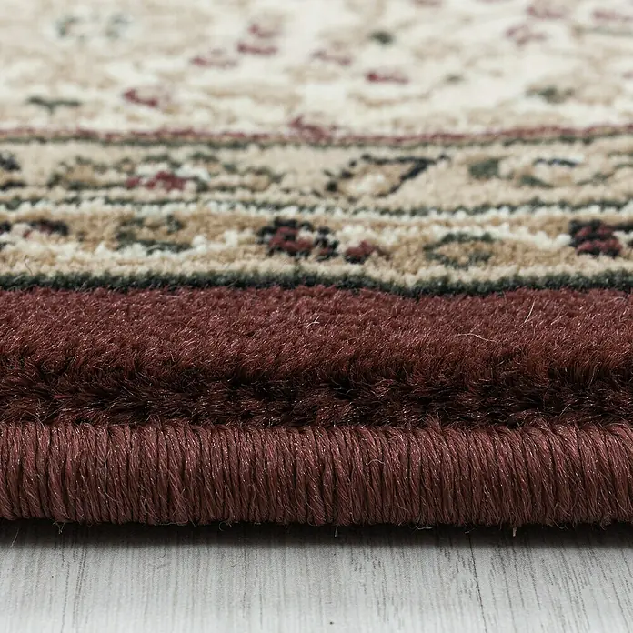 Kurzflorteppich Kashmir 2601Rot, 150 x 80 cm, 100% Polypropylen - Detailaufnahme eines Teppichs mit floralem Muster und bordeauxrotem Rand. Die Textur und die Farben des Teppichs sind gut zu erkennen.