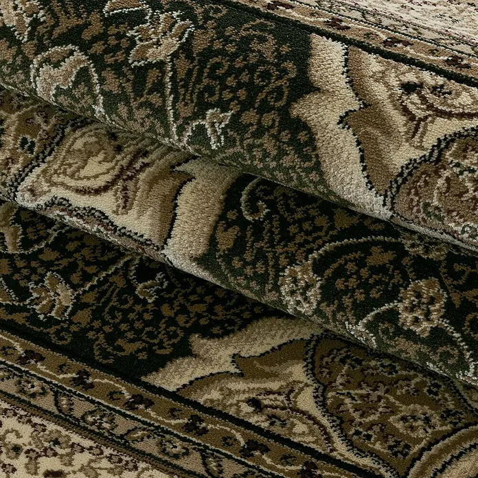 Kurzflorteppich Kashmir 2601 - Grün, 230 x 160 cm, 100 % Polypropylen - Nahaufnahme eines gerollten Teppichs mit einem detailreichen, klassischen Muster in Erd- und Grüntönen. Der Teppich zeigt verschlungene Ornamente und wirkt sehr hochwertig.
