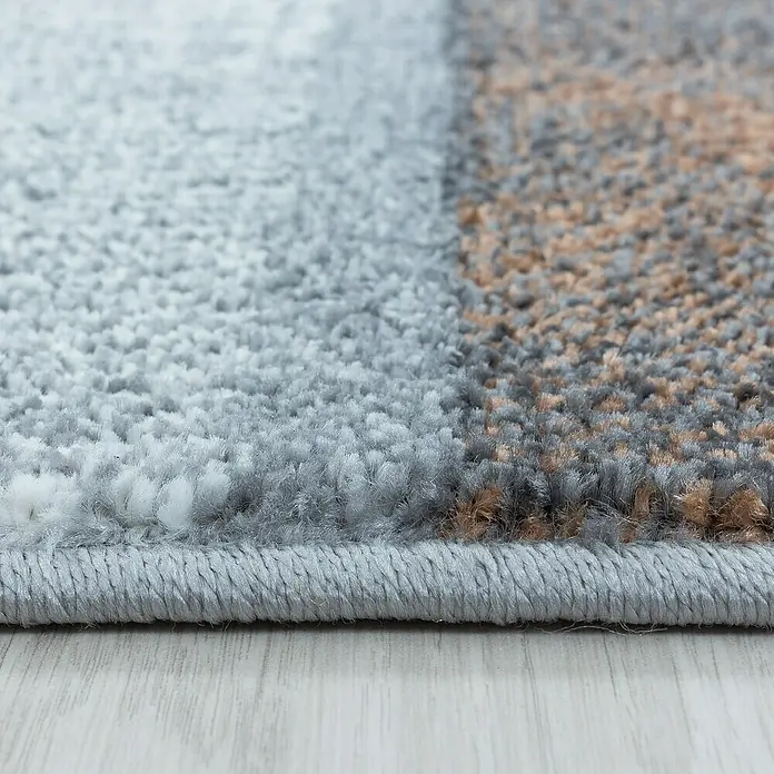 Kurzflorteppich Ottawa 4201 - Kupfer, 200 x 140 cm, 100% Polypropylen - Nahaufnahme eines Teppichs mit abstraktem Muster und grauer Bordüre, der eine weiche Textur und hochwertige Verarbeitung zeigt.