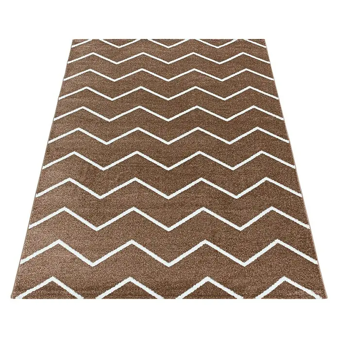 Hochflorteppich Rio 4602 - Kupfer, 200 x 140 cm, 100% Polypropylen - Ein brauner Teppich mit einem Zickzackmuster in Weiß. Der Teppich ist rechteckig und liegt auf einem dunklen Untergrund.