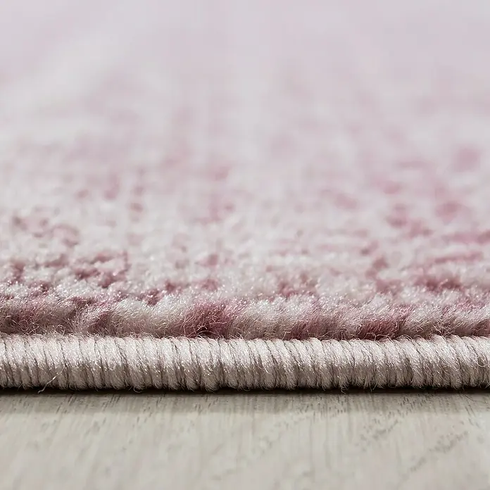 Kurzflorteppich Plus 8000 - Pink, 340 x 240 cm, 100 % Polypropylen - Nahaufnahme eines rosafarbenen Teppichs mit gewebter Kante, der die Textur und die Farbpalette des Produkts hervorhebt.