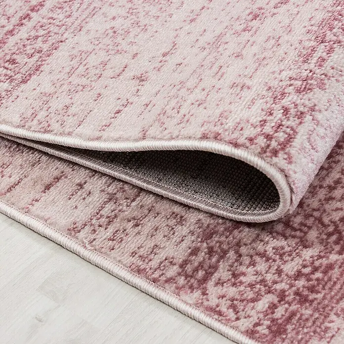 Kurzflorteppich Plus 8000 - Pink, 340 x 240 cm, 100 % Polypropylen - Nahaufnahme eines dekorativen, rosafarbenen Teppichs mit abstraktem Muster und gewebter Bordüre.