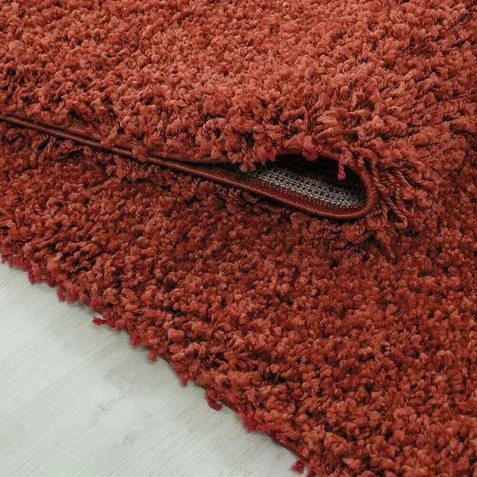 Hochflorteppich Life 1500 - Terra, 150 x 80 cm, 100% Polypropylen - Detailaufnahme eines roten Hochflorteppichs, der dessen weiche Textur und dichte Fasern hervorhebt.